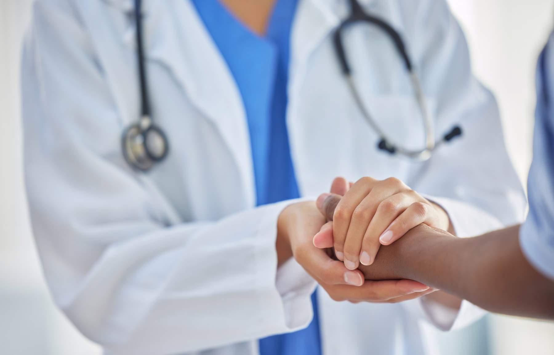Mani di una professionista sanitaria e di una paziente in un gesto di ascolto